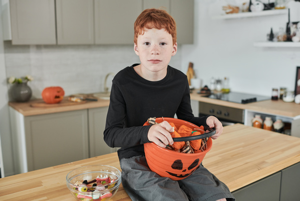 Boy Holds Bucket with Halloween Bundles in Shape of Pumpkin